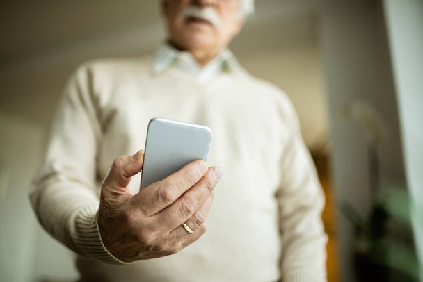 Close-up of mature man using smart phone at home.  - 写真・画像