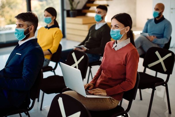 Female entrepreneur using laptop while being on a business seminar during coronavirus pandemic. - Foto, Imagen