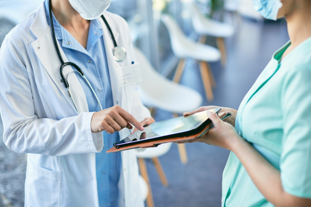 Unrecognizable nurse holding digital tablet while doctor is signing on it in the hospital. - Fotó, kép