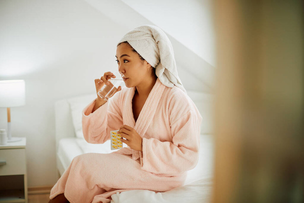 Mladá asijská žena přičemž její omega-3 vitamíny se sklenicí vody doma. - Fotografie, Obrázek