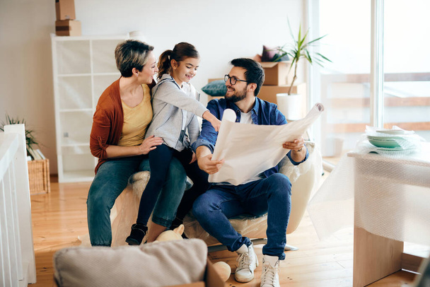 Happy parents and their daughter analyzing housing plans of their new home.  - Zdjęcie, obraz