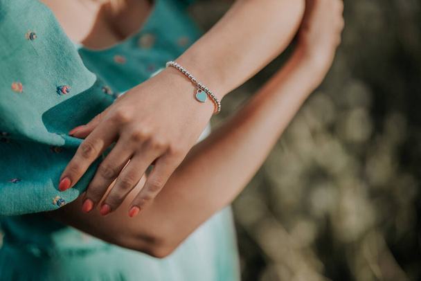 Female hand with silver beads bracelet and blue heart charm. Turquoise jewelry accessories. High quality photo - Valokuva, kuva