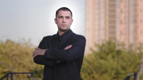Portrait of confident strong caucasian businessman adult brunet man guy wears formal black suit posing with crossed arms outside handsome male professional boss downtown office skyscraper background - Πλάνα, βίντεο