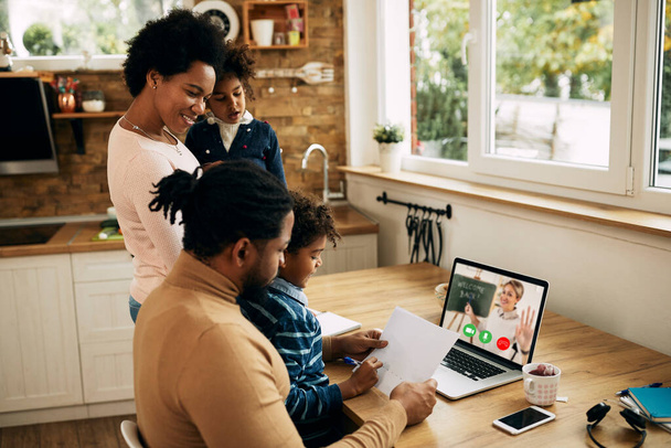 Щаслива афро-американська жінка нагадала чоловікові, щоб він закінчив роботу на ноутбуці, щоб діти могли ходити в Інтернеті на уроки вдома..  - Фото, зображення