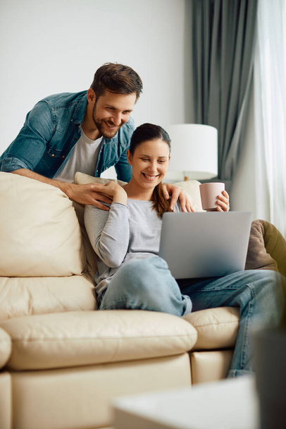 Happy woman and her husband surfing the net on laptop in the living room. - Foto, immagini