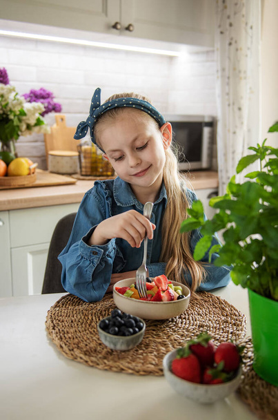 Healthy food at home. Cute little girl eats fruit salad  - Foto, immagini