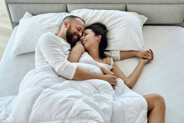 Высокий угол обзора счастливой пары, развлекающейся, просыпаясь вместе утром.  - Фото, изображение
