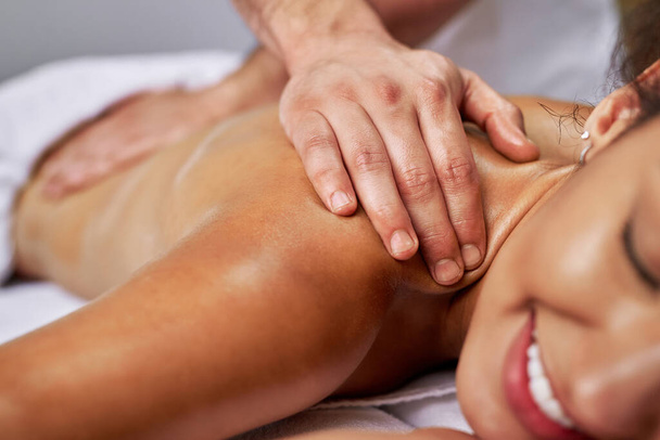 Close-up of massage therapist massaging woman's back at health spa.  - 写真・画像