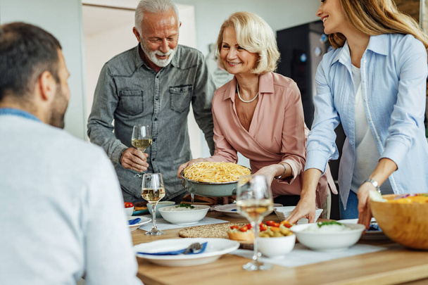 Щаслива сім'я розмовляє під час приготування обіднього столу. Фокус на старшій жінці
. - Фото, зображення