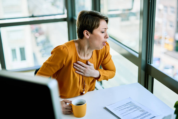 Businesswoman felling sick and coughing while working at her office desk.  - Foto, immagini