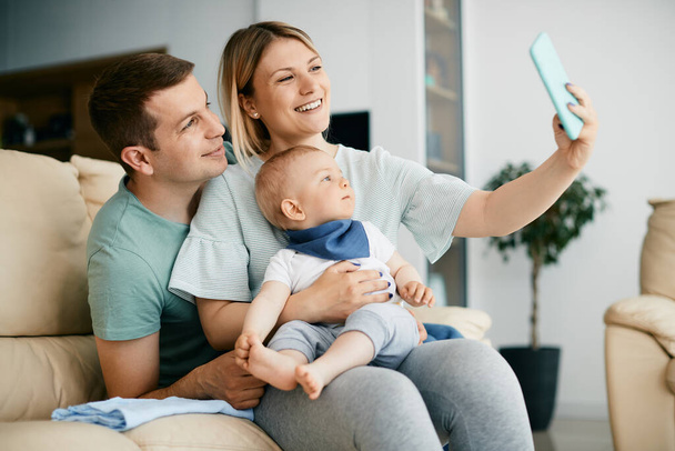 Young happy parents taking selfie with their baby boy while spending time together at home.  - Foto, immagini
