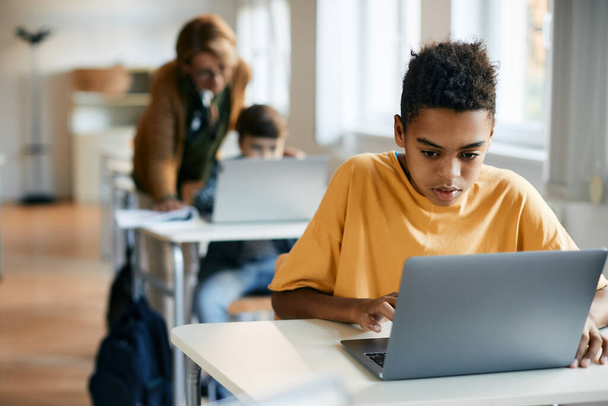 Αφρο-αμερικανική στοιχειώδης μαθητής e-learning στο φορητό υπολογιστή στην τάξη. - Φωτογραφία, εικόνα
