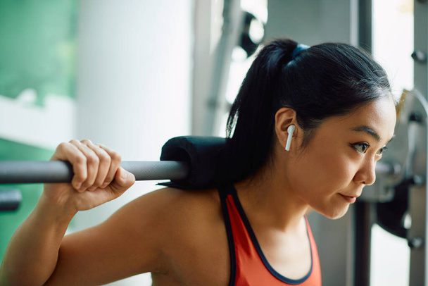 Mladá asijská atletická žena dělá záda cvičení s činkou při sportovním tréninku v tělocvičně. - Fotografie, Obrázek
