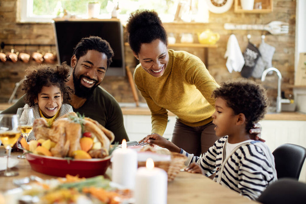 Glückliche schwarze Familie mit Truthahnbraten zum Mittagessen, während sie zu Hause Thanksgiving feiert.  - Foto, Bild