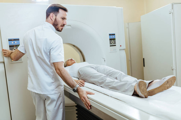 Medical technician starting MRI scanning examination of a female patient at medical clinic.  - Фото, изображение