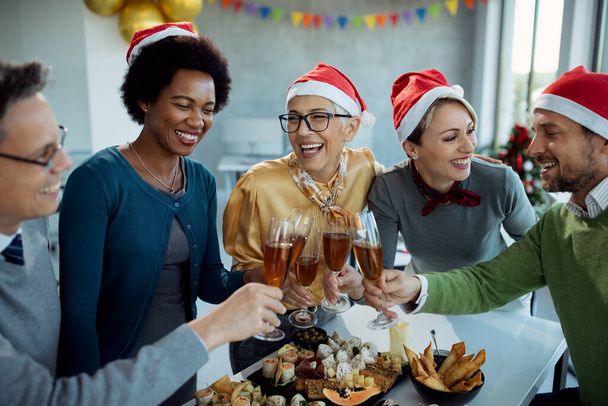 Gruppe glücklicher Unternehmer, die Spaß haben und mit Champagner anstoßen, während sie das neue Jahr auf einer Party im Büro feiern.  - Foto, Bild