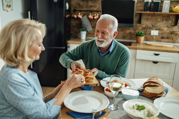 Boldog idős férfi és a felesége esznek az ebédlőasztalnál. Koncentrálj az emberre..  - Fotó, kép