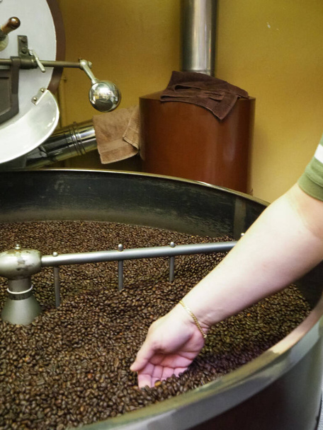Свежеобжаренные кофейные зерна, выливающиеся из большой кофейной жаровни в охлаждающий цилиндр
. - Фото, изображение