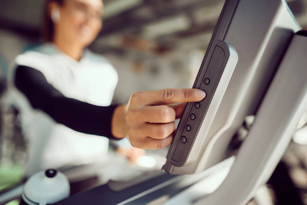 Close-up of sportswoman adjusting speed while running on treadmill in a gym. - Foto, immagini
