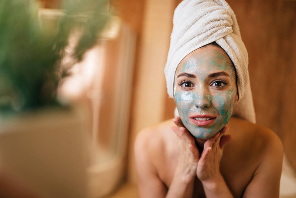 Young beautiful woman with a detox mas on her face in the bathroom.  - Valokuva, kuva