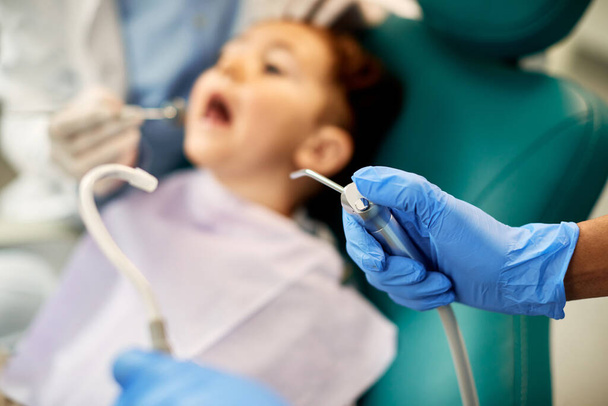Close-up of stomatologist using dental equipment during child's dental check-up. - Foto, Imagen