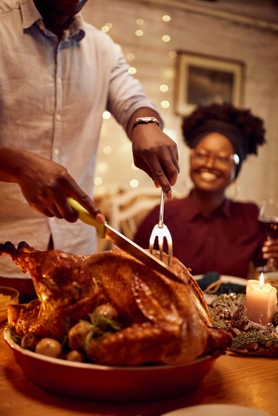 Close-up of African American man carving traditional turkey meat during Thanksgiving lunch at home,  - Foto, Bild