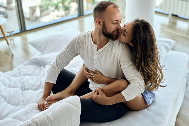 Молодая пара проявляет привязанность и поцелуи во время отдыха в спальне утром.  - Фото, изображение
