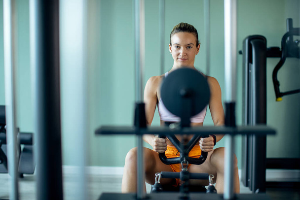 Dedicated athletic woman having cross training on rowing machine in health club. Copy space.  - Photo, image