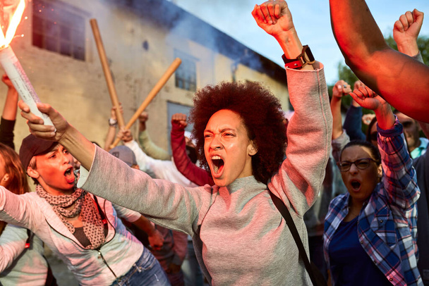 Чорношкіра жінка і група активістів кричать, протестуючи за права людини на вулицях
.  - Фото, зображення