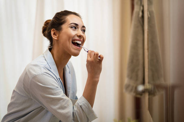 Happy woman cleaning her teeth with a toothbrush in the morning.  - Foto, imagen