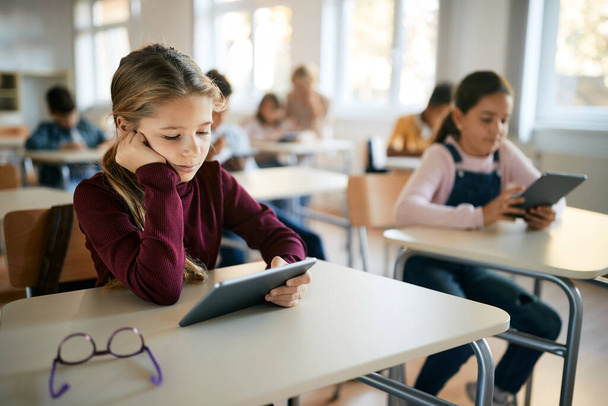 Μαθήτρια που διαβάζει σε ψηφιακό tablet στην τάξη στο δημοτικό σχολείο.  - Φωτογραφία, εικόνα