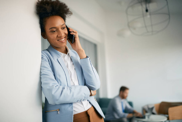 Happy black businesswoman making a phone call while working in the office. - Foto, Imagen