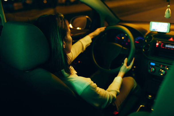 Zadní pohled na ženu těší v noci jízda jejím autem.  - Fotografie, Obrázek