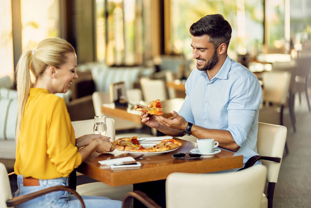 Щасливий чоловік і його дівчина мають піцу на обід в ресторані
.  - Фото, зображення