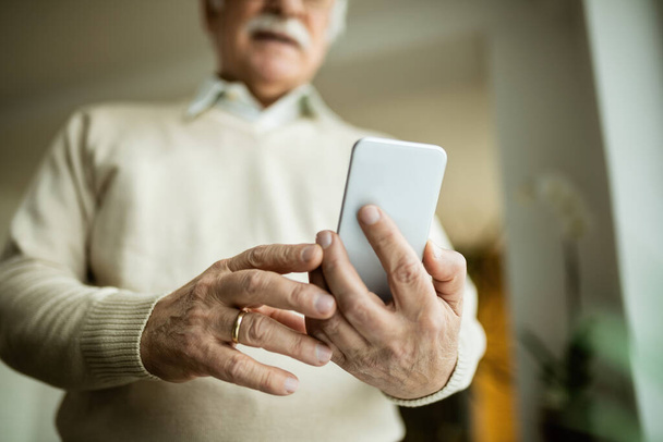Close-up of senior man text messaging on mobile phone.  - Zdjęcie, obraz