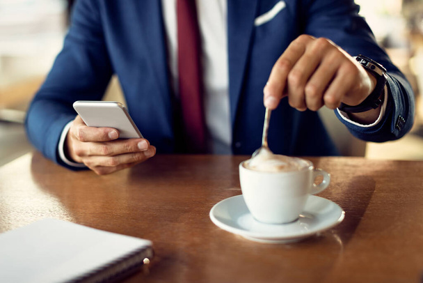 Close-up of businessman texting on mobile phone while drinking coffee in a cafe.  - Foto, immagini