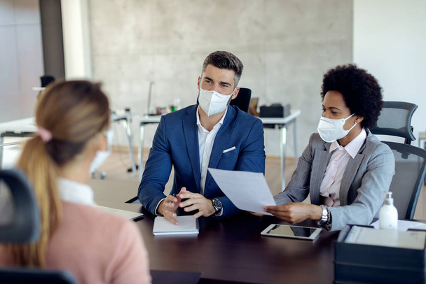 Members of human resource team wearing protective face masks while communicating with a candidate during job interview in the office.  - Foto, Imagen