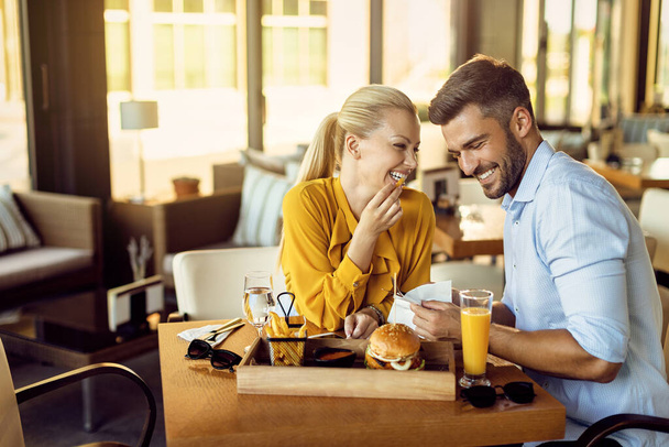Happy couple talking and having fun while eating in a restaurant.  - Foto, imagen