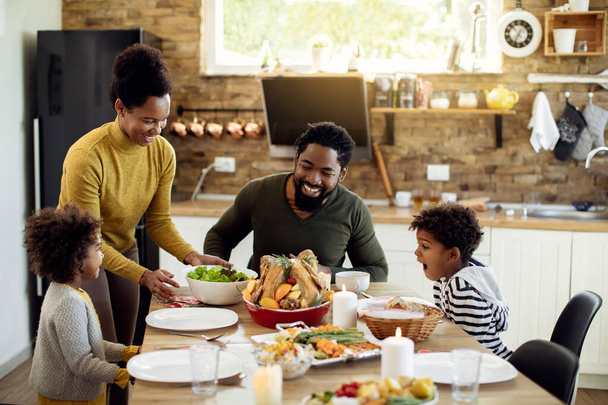 Happy African American parents and their kids having Thanksgiving lunch at home.  - Фото, изображение