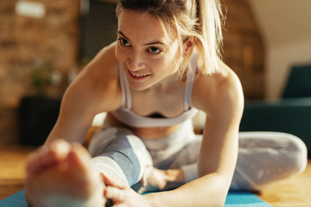 Щаслива жінка-спортсменка розтягує ногу під час тренувань вдома
.  - Фото, зображення