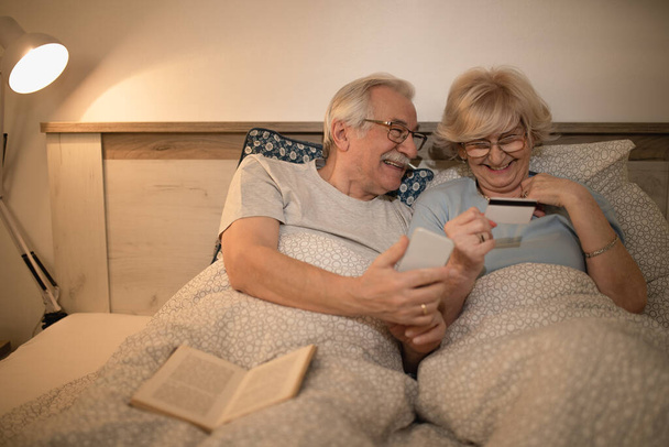 Šťastný starší pár baví při používání chytrého telefonu a nákupu na internetu s jejich kreditní kartou.  - Fotografie, Obrázek
