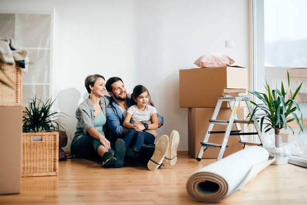 Happy parents and daughter moving into their first home and relaxing on the floor. Copy space. - Fotó, kép