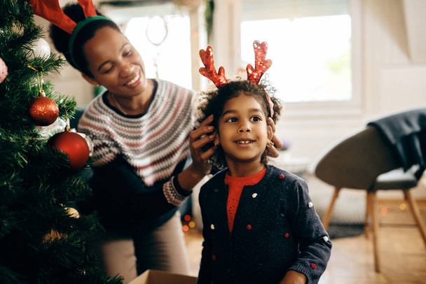 Happy African American daughter and mother enjoying in Christmas preparations at home.  - 写真・画像
