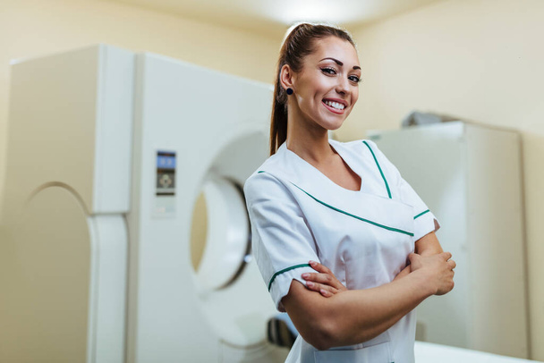 Portrait of confident female radiologist in front of CAT scan machine at medical clinic.  - Zdjęcie, obraz