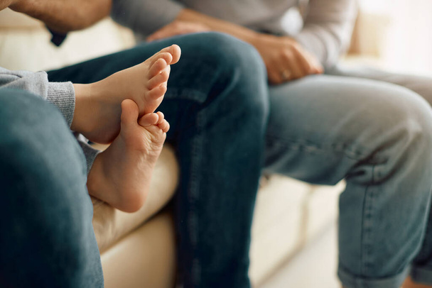 Close-up of child and his parents relaxing on the sofa in the living room. Focus is on child's feet.  - Foto, imagen