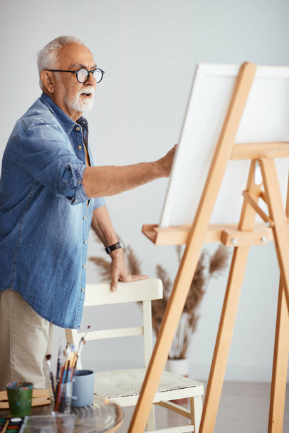 Senior artist painting on canvas at his studio. - Fotografie, Obrázek