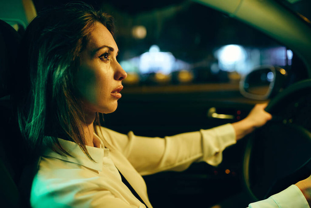 Young woman feeling sad and crying while driving car alone at night.  - Φωτογραφία, εικόνα