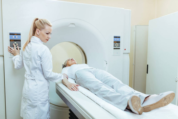 Female doctor starting CT scan procedure of senior patient at medical clinic.  - 写真・画像