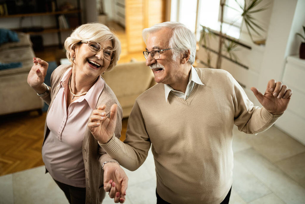 Blick aus der Vogelperspektive auf unbeschwerte Senioren, die beim Tanzen zu Hause Spaß haben.  - Foto, Bild