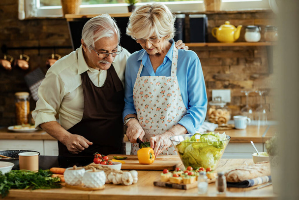 Happy senior couple making a healthy meal while cooking together in the kitchen.  - 写真・画像